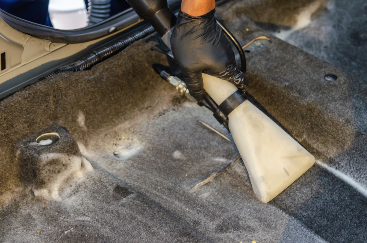Deep cleaning a car's carpet with an extraction tool