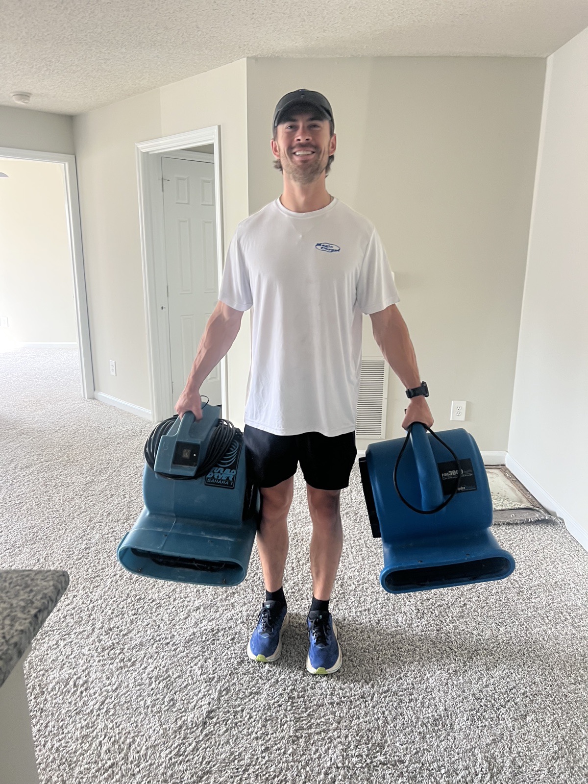 Robbie carrying two air movers on a job